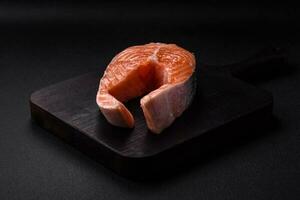 Fresh raw salmon steak with spices and herbs prepared for grilled baking photo