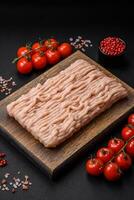 Fresh minced chicken with salt, spices and herbs on a wooden cutting board photo