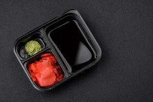 Pickled ginger, soy sauce and wasabi in portioned plastic containers photo