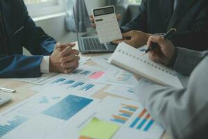 Group of confident business people point to graphs and charts to analyze market data, balance sheet, account, net profit to plan new sales strategies to increase production capacity. photo