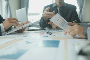Group of confident business people point to graphs and charts to analyze market data, balance sheet, account, net profit to plan new sales strategies to increase production capacity. photo