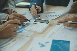 Group of confident business people point to graphs and charts to analyze market data, balance sheet, account, net profit to plan new sales strategies to increase production capacity. photo