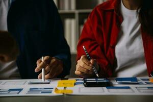 Close up ux developer and ui designer brainstorming about mobile app interface wireframe design on table with customer breif and color code at modern office.Creative digital development agency photo