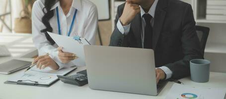 Group of confident business people point to graphs and charts to analyze market data, balance sheet, account, net profit to plan new sales strategies to increase production capacity. photo