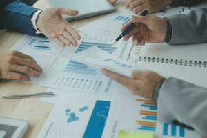 Group of confident business people point to graphs and charts to analyze market data, balance sheet, account, net profit to plan new sales strategies to increase production capacity. photo