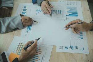 Group of confident business people point to graphs and charts to analyze market data, balance sheet, account, net profit to plan new sales strategies to increase production capacity. photo
