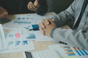 Group of confident business people point to graphs and charts to analyze market data, balance sheet, account, net profit to plan new sales strategies to increase production capacity. photo