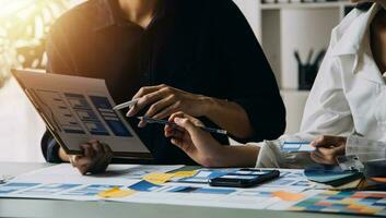 Close up ux developer and ui designer brainstorming about mobile app interface wireframe design on table with customer breif and color code at modern office.Creative digital development agency photo