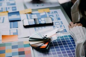 Close up ux developer and ui designer brainstorming about mobile app interface wireframe design on table with customer breif and color code at modern office.Creative digital development agency photo