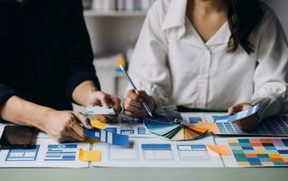 Close up ux developer and ui designer brainstorming about mobile app interface wireframe design on table with customer breif and color code at modern office.Creative digital development agency photo