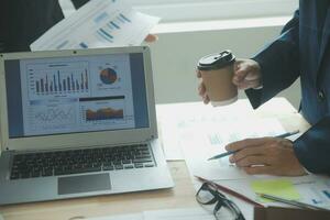 Group of confident business people point to graphs and charts to analyze market data, balance sheet, account, net profit to plan new sales strategies to increase production capacity. photo