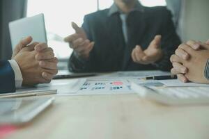 Group of confident business people point to graphs and charts to analyze market data, balance sheet, account, net profit to plan new sales strategies to increase production capacity. photo