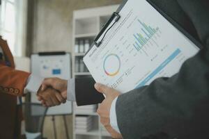 Group of confident business people point to graphs and charts to analyze market data, balance sheet, account, net profit to plan new sales strategies to increase production capacity. photo