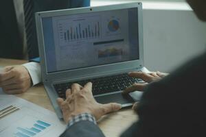 Group of confident business people point to graphs and charts to analyze market data, balance sheet, account, net profit to plan new sales strategies to increase production capacity. photo