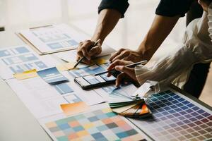 Close up ux developer and ui designer brainstorming about mobile app interface wireframe design on table with customer breif and color code at modern office.Creative digital development agency photo