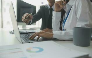 Group of confident business people point to graphs and charts to analyze market data, balance sheet, account, net profit to plan new sales strategies to increase production capacity. photo