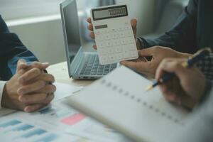 grupo de empresarios confiados señalan gráficos y cuadros para analizar datos de mercado, balance, cuenta, beneficio neto para planificar nuevas estrategias de ventas para aumentar la capacidad de producción. foto