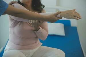 young asian physical therapist working with senior woman on walking with a walker photo