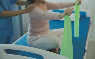 young asian physical therapist working with senior woman on walking with a walker photo