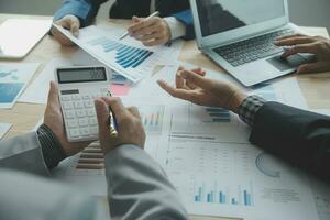 Group of confident business people point to graphs and charts to analyze market data, balance sheet, account, net profit to plan new sales strategies to increase production capacity. photo
