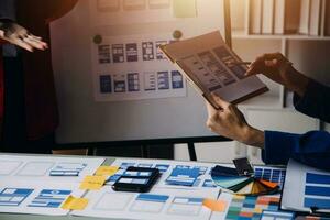 Close up ux developer and ui designer brainstorming about mobile app interface wireframe design on table with customer breif and color code at modern office.Creative digital development agency photo