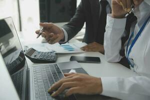 Group of confident business people point to graphs and charts to analyze market data, balance sheet, account, net profit to plan new sales strategies to increase production capacity. photo