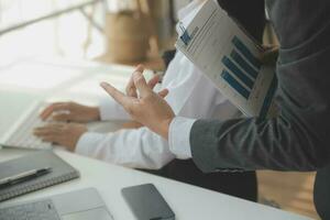Group of confident business people point to graphs and charts to analyze market data, balance sheet, account, net profit to plan new sales strategies to increase production capacity. photo