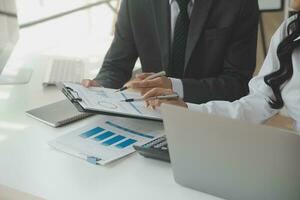 Group of confident business people point to graphs and charts to analyze market data, balance sheet, account, net profit to plan new sales strategies to increase production capacity. photo