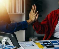Close up ux developer and ui designer brainstorming about mobile app interface wireframe design on table with customer breif and color code at modern office.Creative digital development agency photo
