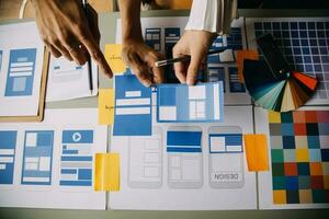 Close up ux developer and ui designer brainstorming about mobile app interface wireframe design on table with customer breif and color code at modern office.Creative digital development agency photo