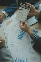 Group of confident business people point to graphs and charts to analyze market data, balance sheet, account, net profit to plan new sales strategies to increase production capacity. photo