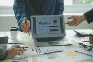 Group of confident business people point to graphs and charts to analyze market data, balance sheet, account, net profit to plan new sales strategies to increase production capacity. photo