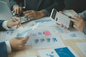 Group of confident business people point to graphs and charts to analyze market data, balance sheet, account, net profit to plan new sales strategies to increase production capacity. photo