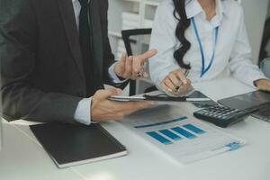 Group of confident business people point to graphs and charts to analyze market data, balance sheet, account, net profit to plan new sales strategies to increase production capacity. photo