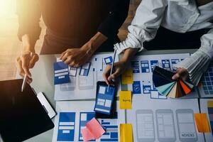 Close up ux developer and ui designer brainstorming about mobile app interface wireframe design on table with customer breif and color code at modern office.Creative digital development agency photo