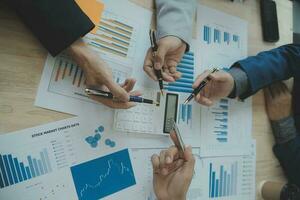Group of confident business people point to graphs and charts to analyze market data, balance sheet, account, net profit to plan new sales strategies to increase production capacity. photo
