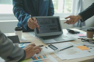 Group of confident business people point to graphs and charts to analyze market data, balance sheet, account, net profit to plan new sales strategies to increase production capacity. photo