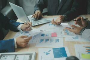 Group of confident business people point to graphs and charts to analyze market data, balance sheet, account, net profit to plan new sales strategies to increase production capacity. photo