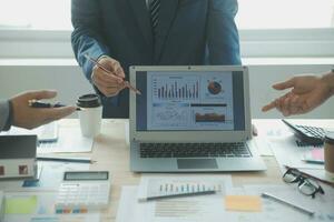 Group of confident business people point to graphs and charts to analyze market data, balance sheet, account, net profit to plan new sales strategies to increase production capacity. photo