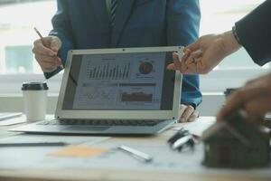Group of confident business people point to graphs and charts to analyze market data, balance sheet, account, net profit to plan new sales strategies to increase production capacity. photo
