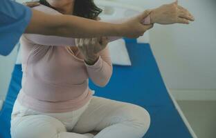 Doctor or physical therapist examines back pain and spinal area to give advice within the rehabilitation center. photo