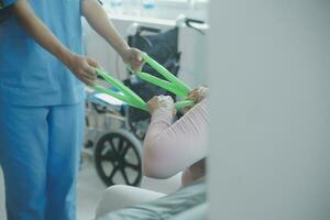 young asian physical therapist working with senior woman on walking with a walker photo