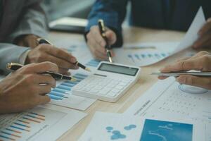 Group of confident business people point to graphs and charts to analyze market data, balance sheet, account, net profit to plan new sales strategies to increase production capacity. photo
