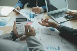 Group of confident business people point to graphs and charts to analyze market data, balance sheet, account, net profit to plan new sales strategies to increase production capacity. photo