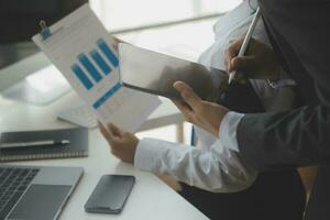 Group of confident business people point to graphs and charts to analyze market data, balance sheet, account, net profit to plan new sales strategies to increase production capacity. photo