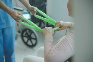 young asian physical therapist working with senior woman on walking with a walker photo