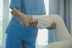 young asian physical therapist working with senior woman on walking with a walker photo