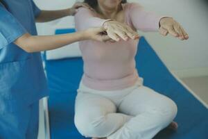 Doctor or physical therapist examines back pain and spinal area to give advice within the rehabilitation center. photo