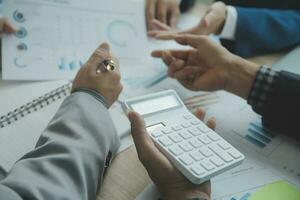 Group of confident business people point to graphs and charts to analyze market data, balance sheet, account, net profit to plan new sales strategies to increase production capacity. photo