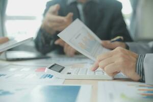 Group of confident business people point to graphs and charts to analyze market data, balance sheet, account, net profit to plan new sales strategies to increase production capacity. photo